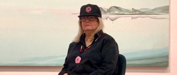 Wanda Koop sits in front of her painting