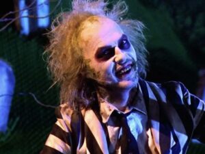 Michael Keaton in white face paint and striped suit as a ghost