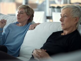 two older women sitting on white couch side view