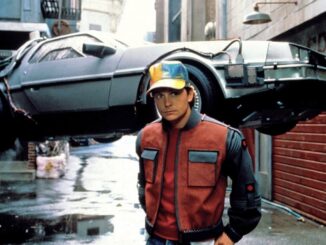 man in puffer jacket in front of Delorean on riser
