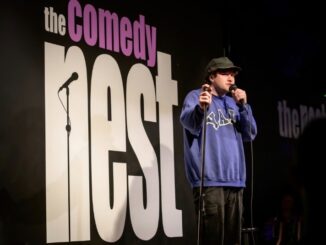 Comedian in front of sign