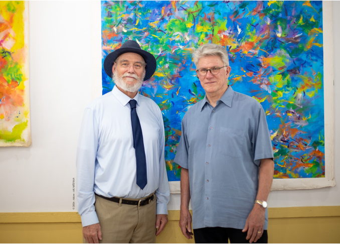 2 men standing in front of a wall of art