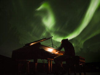 Person at piano with aurora borealis in background